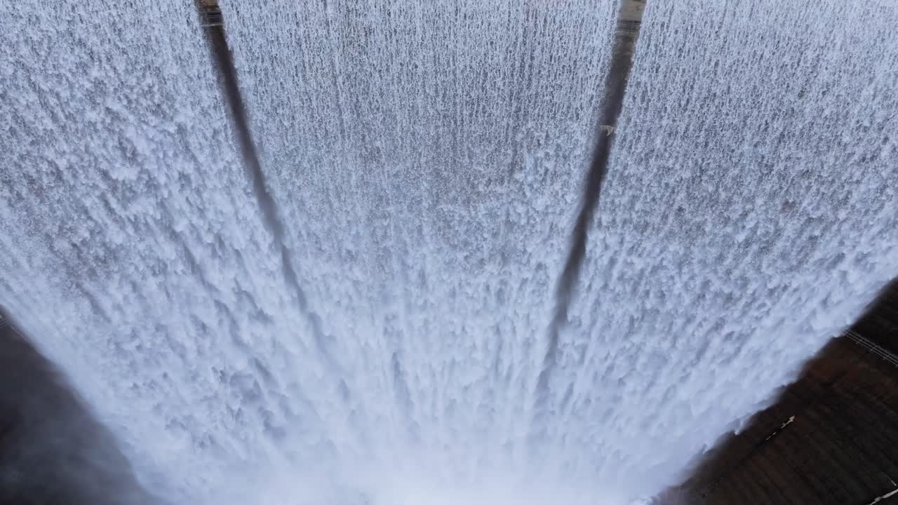 Vista aerea ravvicinata dell'acqua che scende a cascata su uno sfioratore curvo di una diga - Encoro do Eume in Galizia, Spagna. Ripresa con movimento di tilt verso il basso.