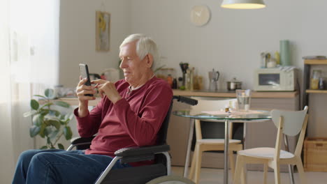 elderly man in wheelchair using smartphone at home