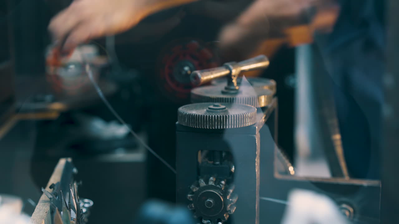jeweler turns handle of machine working with wire closeup