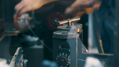 jeweler turns handle of machine working with wire closeup