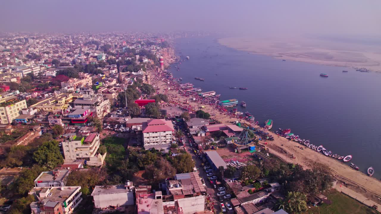 Ganga river with crowded buildings and haze at varanasi, kashi, uttar pradesh, india. day time, moving down, pan shot, drone shot, 4k.