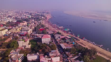 ganga river with crowded buildings and haze at varanasi, kashi, uttar pradesh, india. day time, moving down, pan shot, drone shot, 4k.
