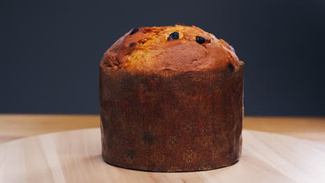 traditional english christmas cake tied with a jute thread on the black background. italian classic panettone .pastry chef sprinkles powdered sugar through a sieve on the fruit easter cake with raisins. high quality 4k footage