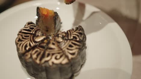 a hand cutting and eating a luxurious decorated mooncake