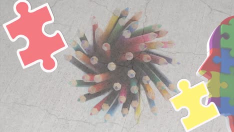 Animation-of-puzzles-falling-over-colourful-pencils-and-human-head-formed-with-puzzles