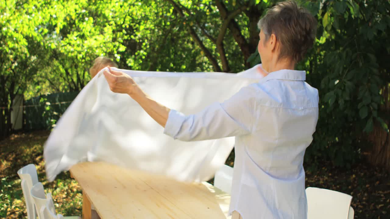 행복 한 고령 여성 이 피크닉 테이블 을 준비 하고 있다