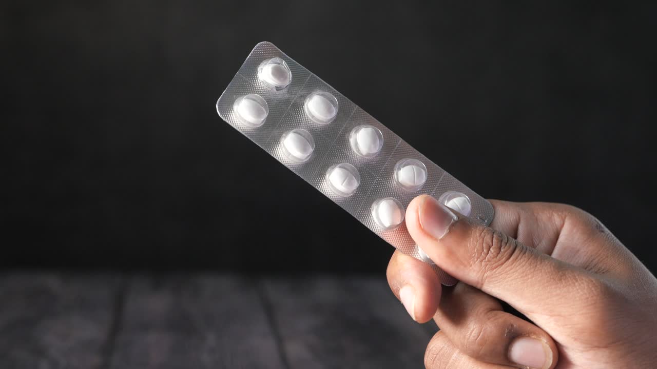 색 알약을 담은 블리스터 패키지를 들고 있는 손
