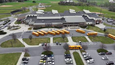 Aerial-of-public-school-campus-in-USA-with-yellow-school-bus-vehicle-to-transport-students