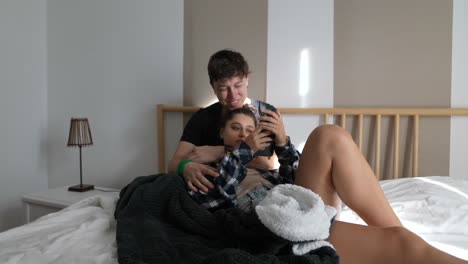 Couple Relaxing on Bed with Smartphone