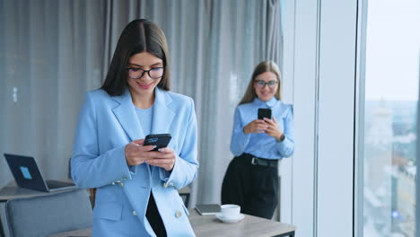happy people working in the office. co workers enjoying free time during lunch break. female colleagues using phones at break. blurred backdrop.