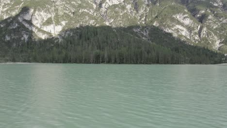 vista lateral del video del dron "deslizador" sobre el lago di landro durrensee de italia con montañas en el horizonte