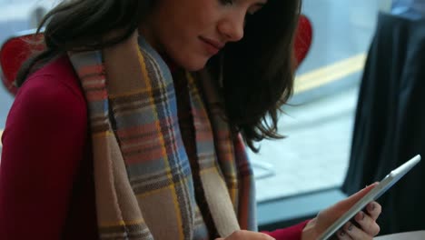 pretty brunette having a coffee in cafe using tablet