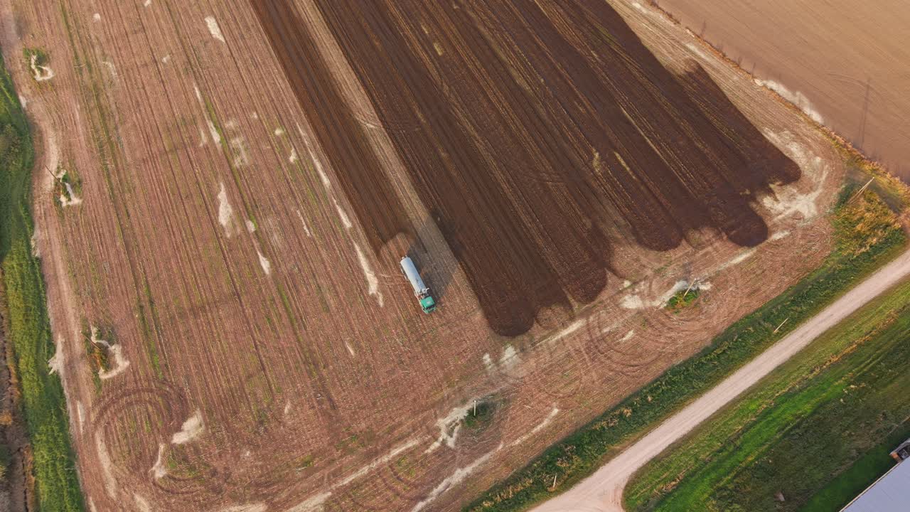 Tractor spraying liquid manure over agricultural farmland Aerial View