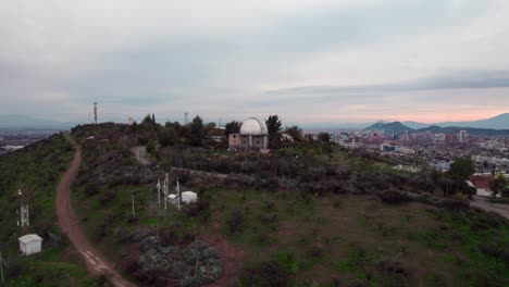 Boom-up-aerial-view-of-Calan-hill-and-the-observatory-at-the-top-in-Las-Condes,-Santiago,-Chile