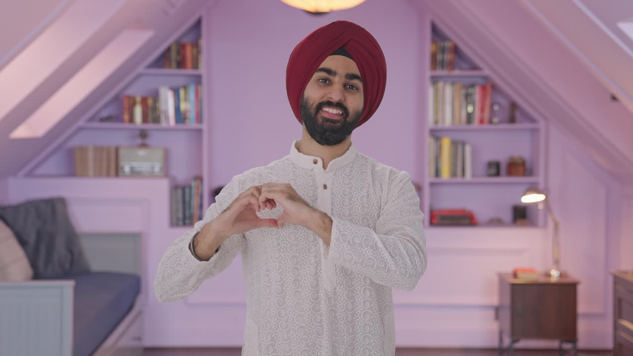 Uomo indiano Sikh felice che mostra il segno del cuore
