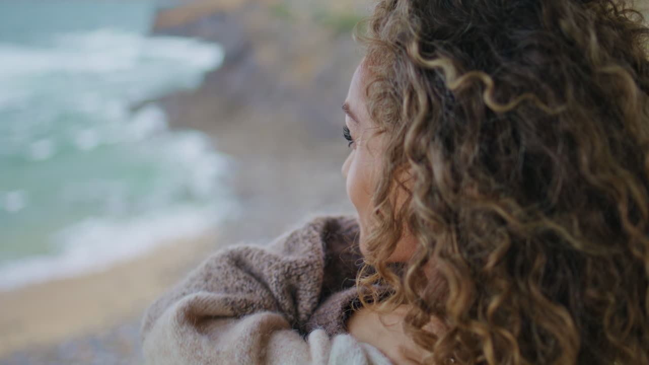 구름이 가득한 바가에서 카메라를 찾는 성숙한 여성. 해안에서 여성의 초상화