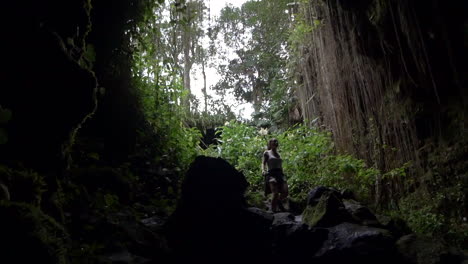 a young woman carefully descending into the dark tranquil kaumana caves, big island of hawaii