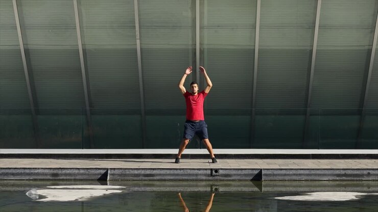 Mexican sports man warming up jumping jack outdoors on sunny day