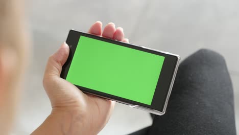 green screen display on mobile phone in blond female hands