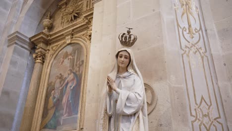 Elegant Virgin Mary statue with crown and rosary, radiating peace in sacred surroundings