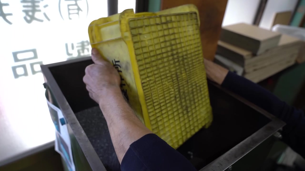 Operaio che versa componenti a vite grigi da un vassoio giallo in una macchina selezionatrice