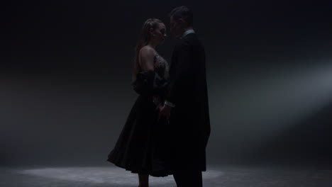 Tender-ballroom-dancers-standing-on-stage.-Beautiful-dance-couple-joining-hands