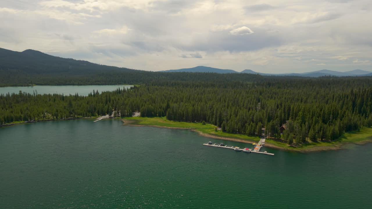 Lava Lake and Little Lava Lake in Central Oregon at the Cascade Lakes Highway. Aerial arc shot around boat dock on the shoreline.