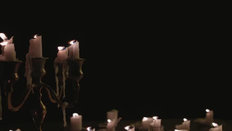 a group of white candles some on a candelabra lit up then blown out by the wind