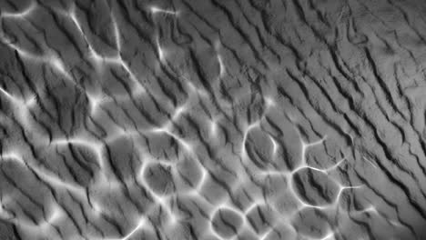 water reflection light pattern on wrinkled black sand surface. abstract natural overlay with wavy lines and sunlight ripple effect. design for wallpaper, banner, postcard, greeting card, poster,