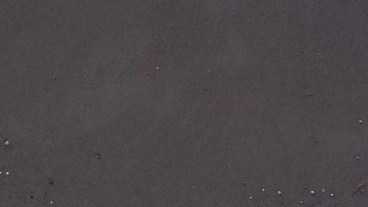 Greece beach aerial view showing dark sand and scattered pebbles