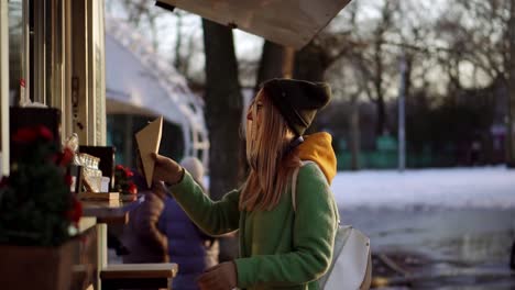 woman buying french fries outdoors on winter street food kiosk