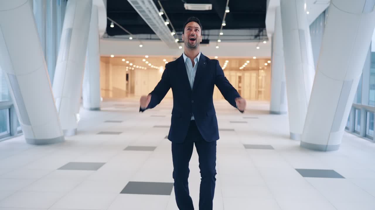 Happy enthusiastic professional man leaping in the air with elation while celebrating a major business victory in a modern corporate hallway