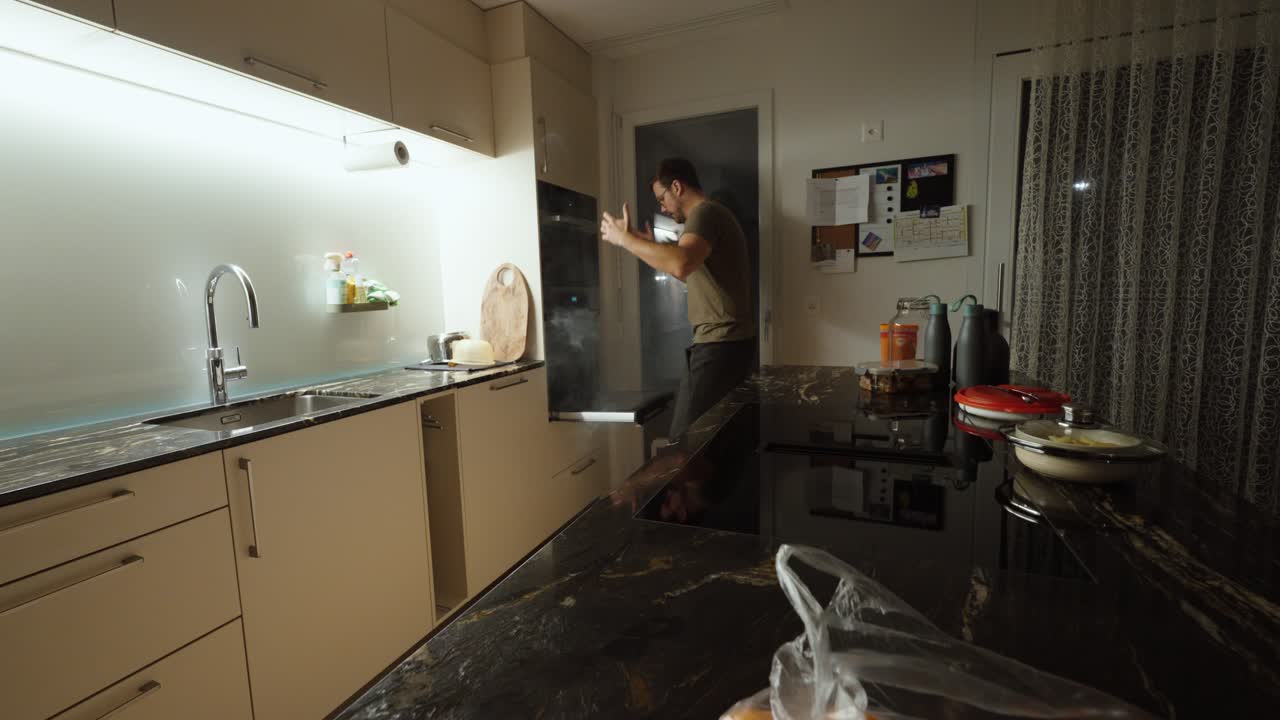 A man quickly runs to his oven as thick smoke pours out, indicating burnt food, kitchen hazards, cooking mistakes, and household emergency situations involving smoke buildup