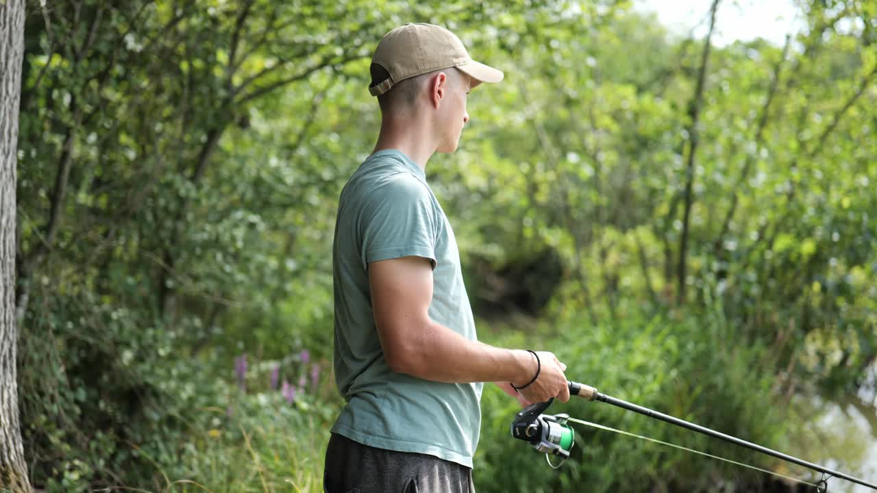 Male angler casting his line with green trees in the background