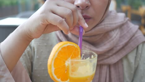 woman drinking orange juice with a straw