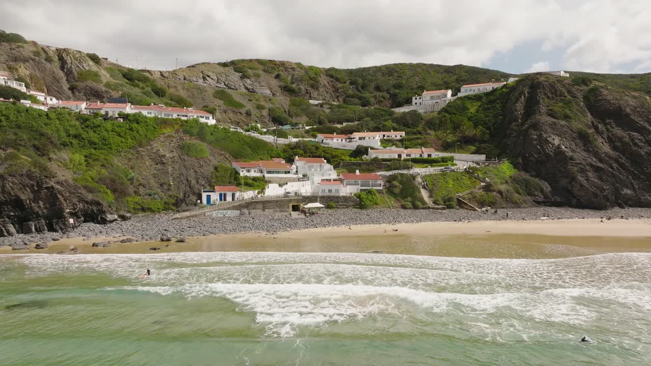 vista aérea volando hacia villas blancas con tejados anaranjados construidos sobre acantilados escarpados a lo largo de una hermosa bahía soleada