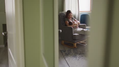 video of happy caucasian mother feeding newborn baby in armchair