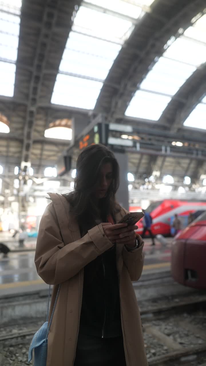 mujer usando el teléfono en la estación de tren