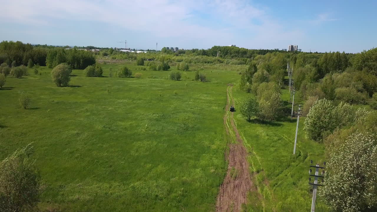 vista aérea de un campo de hierba con un camino de tierra y líneas eléctricas