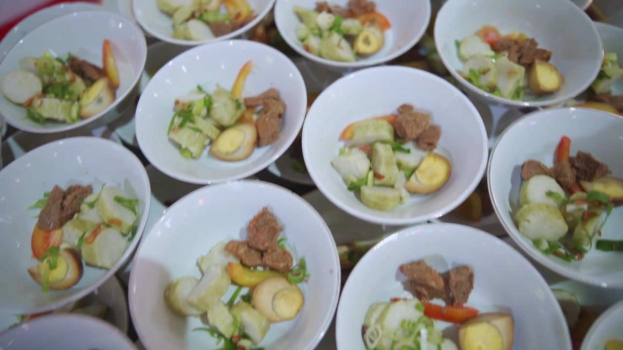 Neat rows of gourmet soup dishes prepared for mass distribution at a luxury banquet