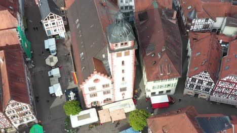 aerial overhead shot of a sunday market on a town square tilting to a european church with birds circling around the tower