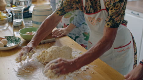 elderly grandmother teaching grandchildren how to knead dough for baking