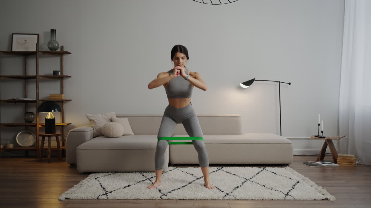 mujer haciendo cuclillas de banda de resistencia en casa