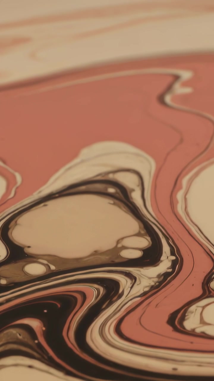 Vertical video: Panning camera revealing art panel on table, paint forming pink cream black cells