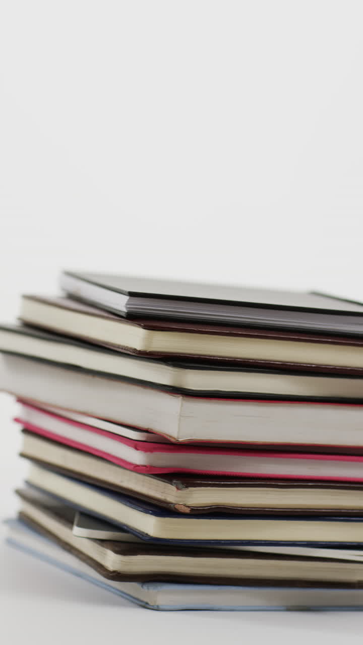 Vertical video of stack of books with copy space on grey background, in slow motion