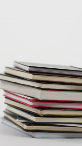 vertical video of stack of books with copy space on grey background, in slow motion