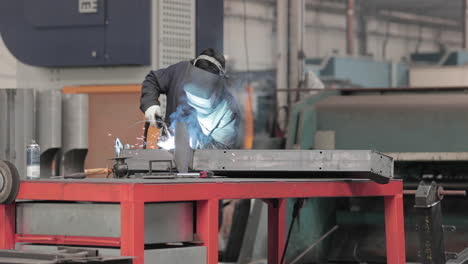 worker welding steel with mig welding machine - medium shot