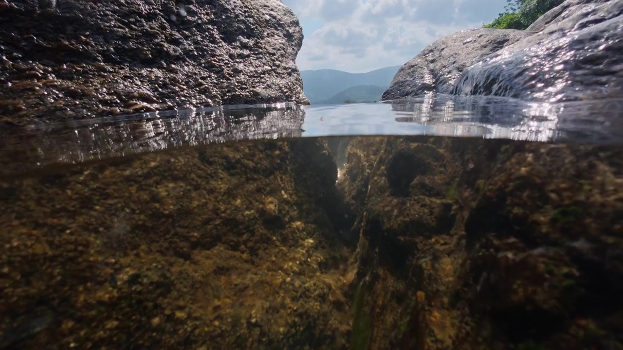 Split level view at Na Muang Waterfall 2 on Koh Samui, Thailand, showing crystal clear freshwater above and below the surface between granite rocks