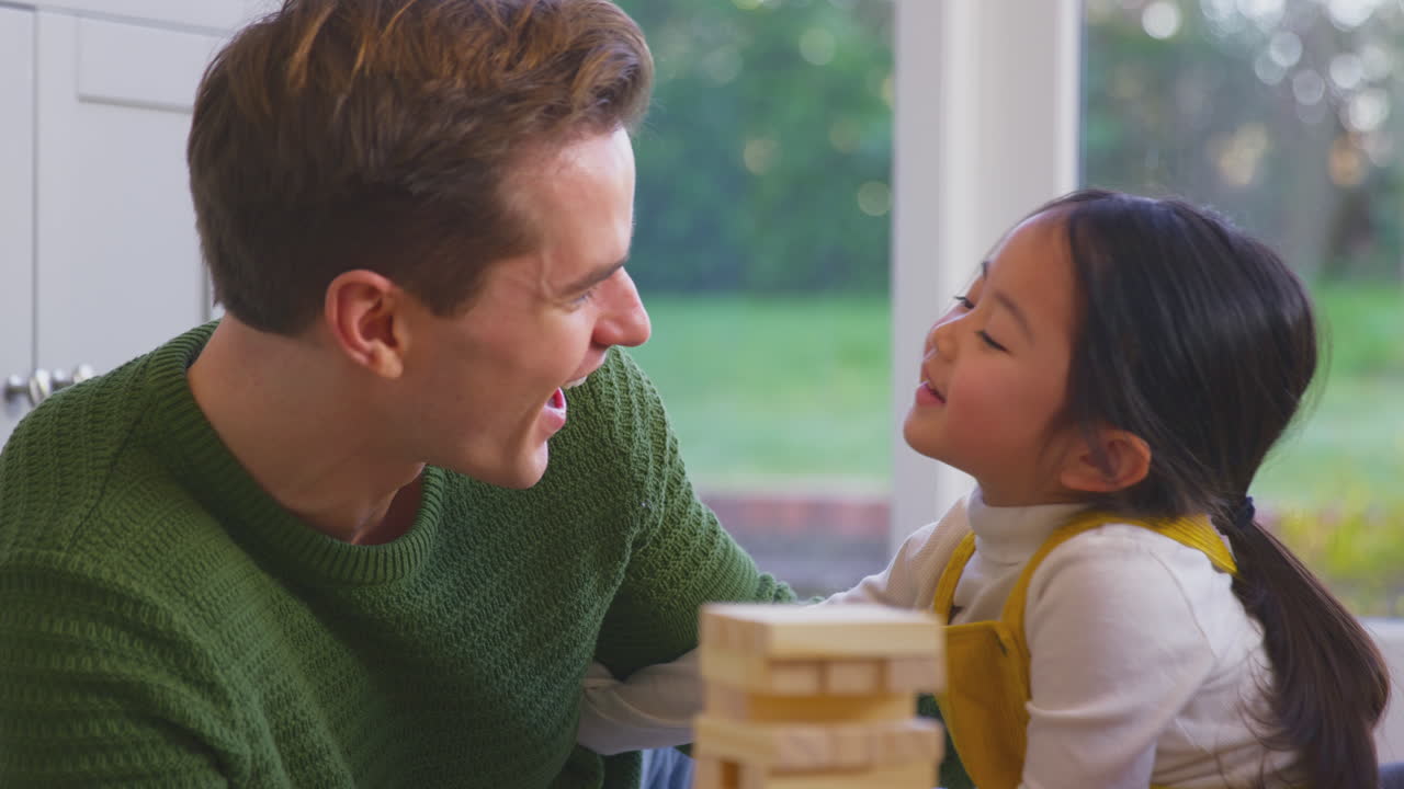 집에서 딸과 함께 게임을 하는 아버지와 함께 나무 벽돌을 탑으로 쌓는 가족