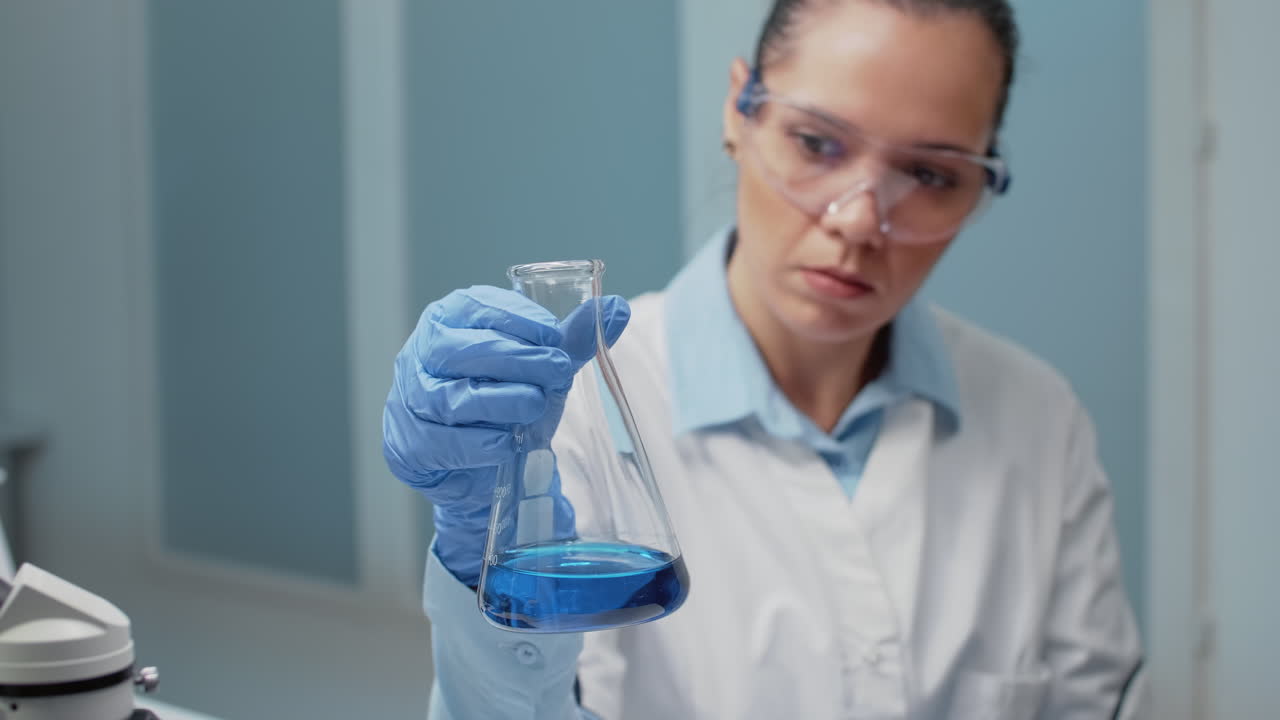 Scientist working in a laboratory with a flask of blue liquid